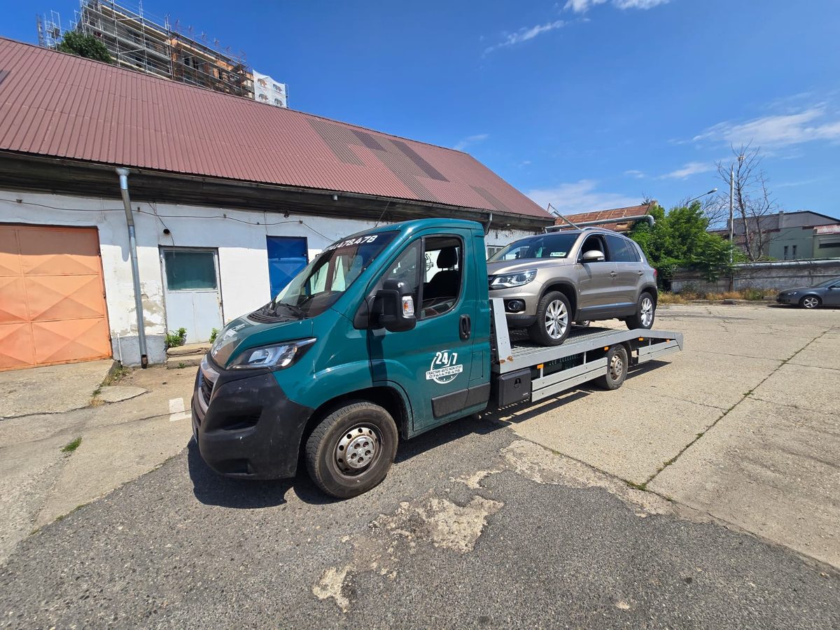 Transport auto la service în București: SUV gri pe autoplatformă