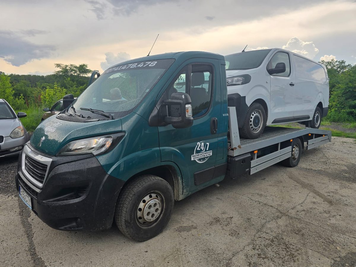 Autoplatformă cu o autoutilitară albă fixată pe platformă, transport în siguranță
